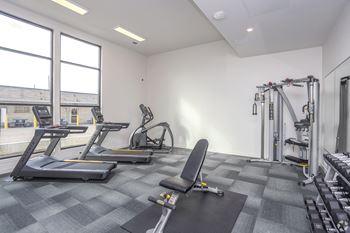 two treadmills and other exercise equipment in a gym with windows